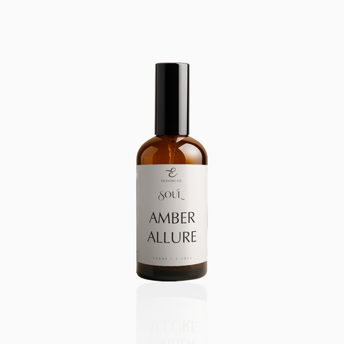 100ml Amber Allure fragrance mist in amber glass bottle with black cap and warm beige label, photographed on white background
