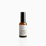 50ml Amber Allure fragrance mist in amber glass bottle with black cap and warm beige label, photographed on white background