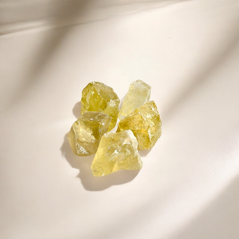 Raw Citrine crystals in warm honey-yellow tones with natural translucency, photographed on a soft cream beige background