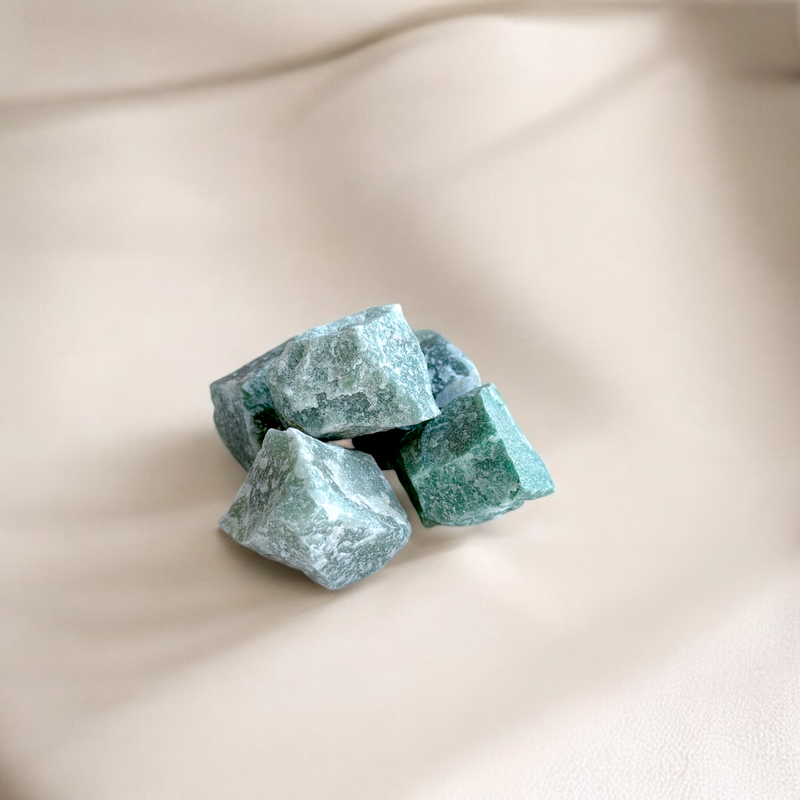 Raw Green Aventurine crystals in muted jade and mint tones with natural matte texture, photographed on a soft beige background