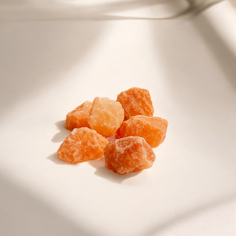 Raw Citrine crystals in warm honey-yellow tones with natural translucency, photographed on a soft beige cream background