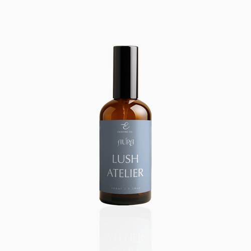 100ml Lush Atelier fragrance mist in amber glass bottle with black cap and muted slate blue label, photographed on white background