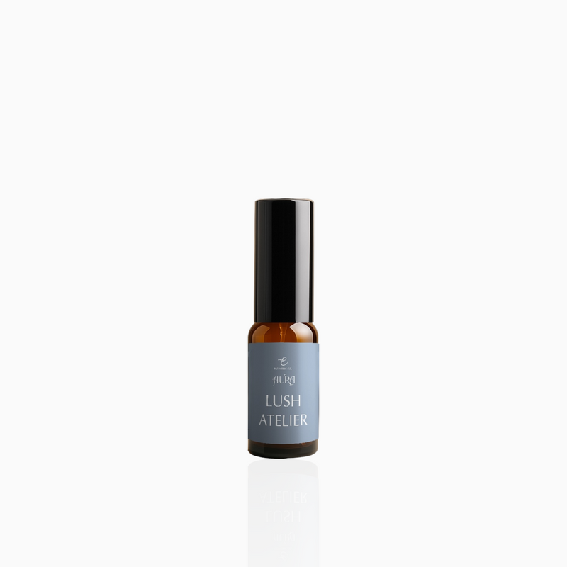 15ml Lush Atelier fragrance mist in amber glass bottle with black cap and muted slate blue label, photographed on white background