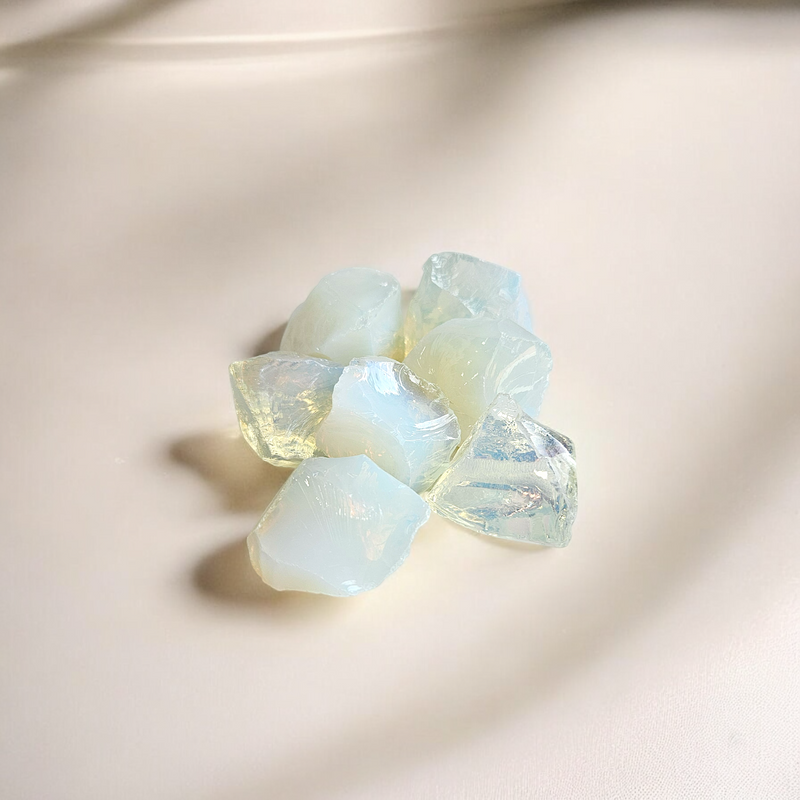 Raw Opalite crystals with a soft milky glow and subtle iridescent sheen, photographed on a light neutral background
