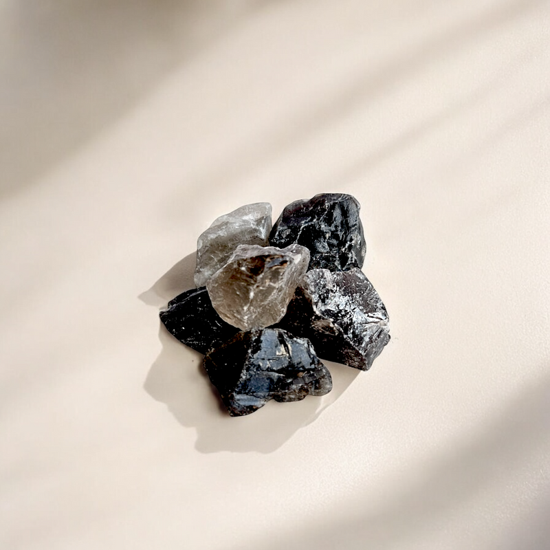 Raw Smokey Quartz crystals in translucent brown to dark grey tones, photographed on a soft neutral background with natural shadows