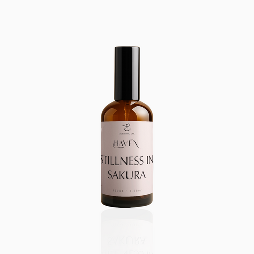 100ml Stillness In Sakura fragrance mist in amber glass bottle with black cap and blush pink label, photographed on white background