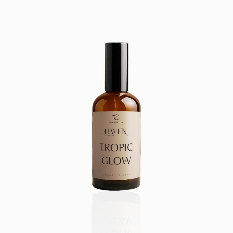 100ml Tropic Glow fragrance mist in amber glass bottle with black cap and beige label, photographed on white background
