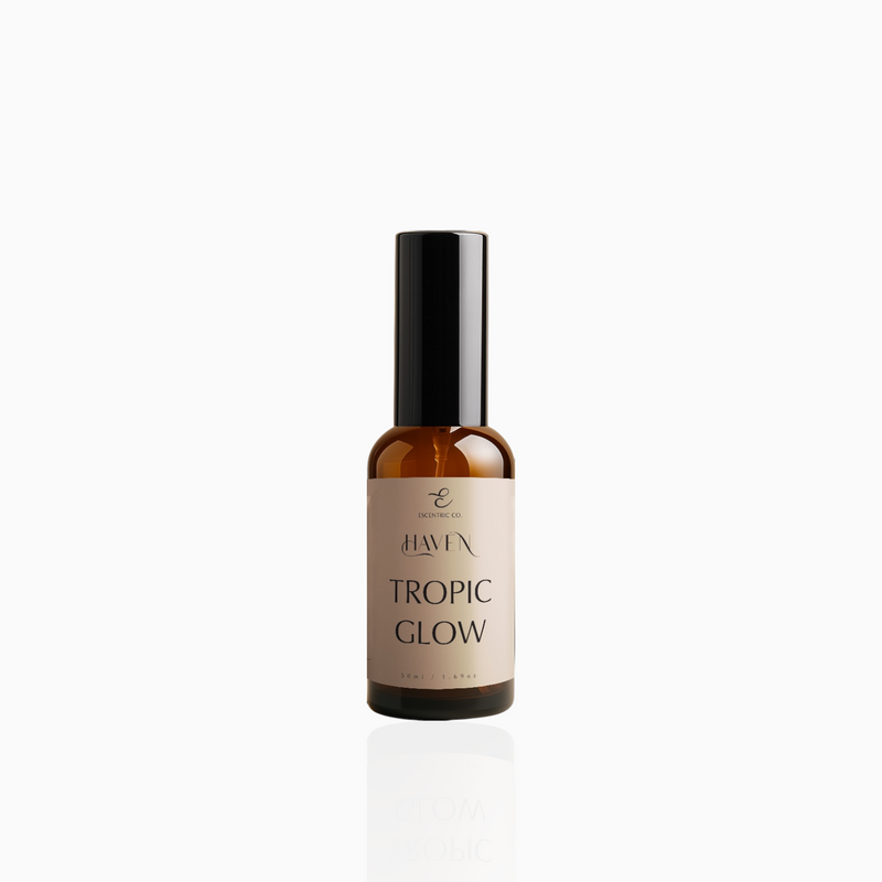 50ml Tropic Glow fragrance mist in amber glass bottle with black cap and beige label, photographed on white background